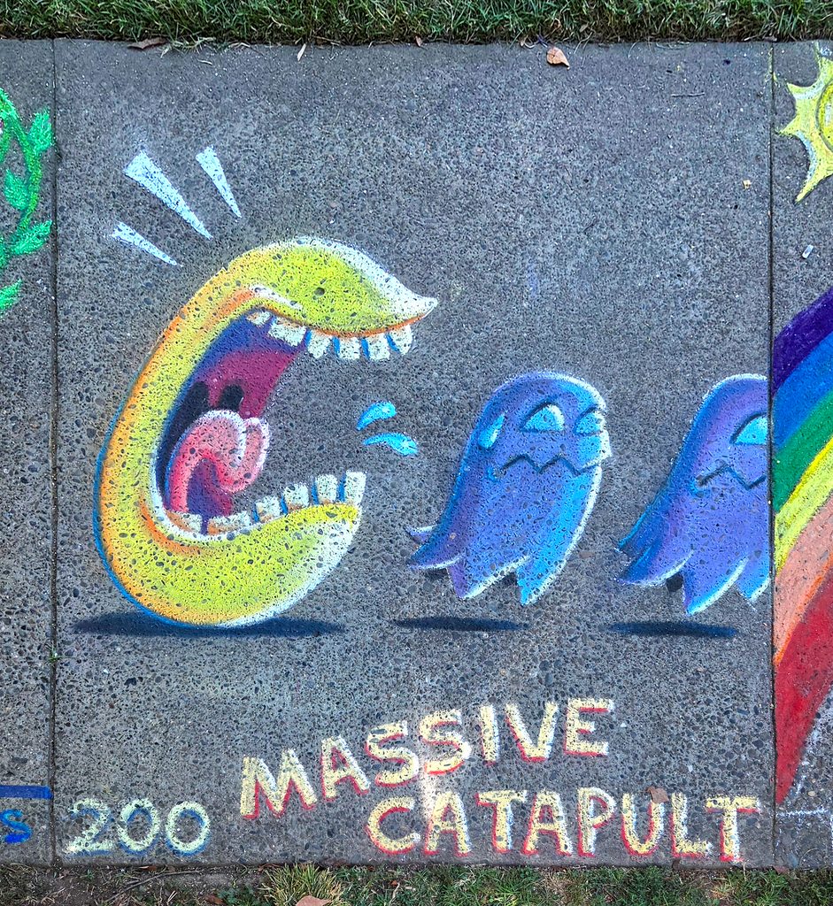 The finished artwork for my Chalk It Up 2026 square with the perspective removed. The illustration is of a Pac-Man with open mouth and teeth chasing two scared ghosts. Underneath is the square number (200) and the words "Massive Catapult", the square's sponsor. You can see grass at the top and bottom of the image and my neighbors' squares to the left and right.
